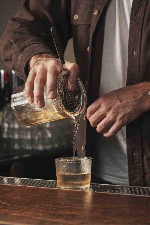 Photo d’un homme qui verse de l'alcool dans un verre.
