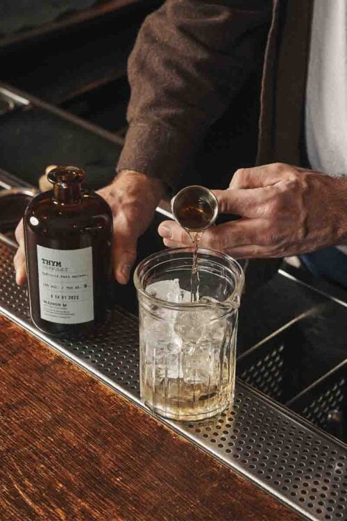 Photo d'un homme en train de servir une dose d'alcool de thym dans un grand verre