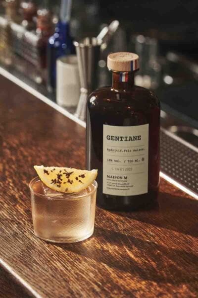 Photo d'un cocktail servi dans un verre avec une bouteille de gentiane