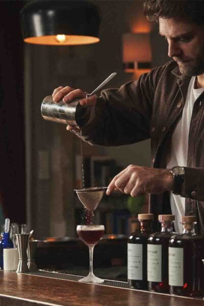 Photo d’un homme qui est en train de servir un cocktail dans un verre à pied.