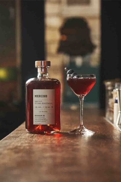 photo d'un cocktail servi dans un verre avec une bouteille d'alcool de merise