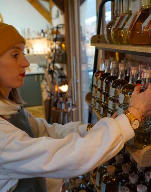 Photo de Roxane Mengoli en train de poser un flacon de spiritueux sur une étagère dans la distillerie Maison M.