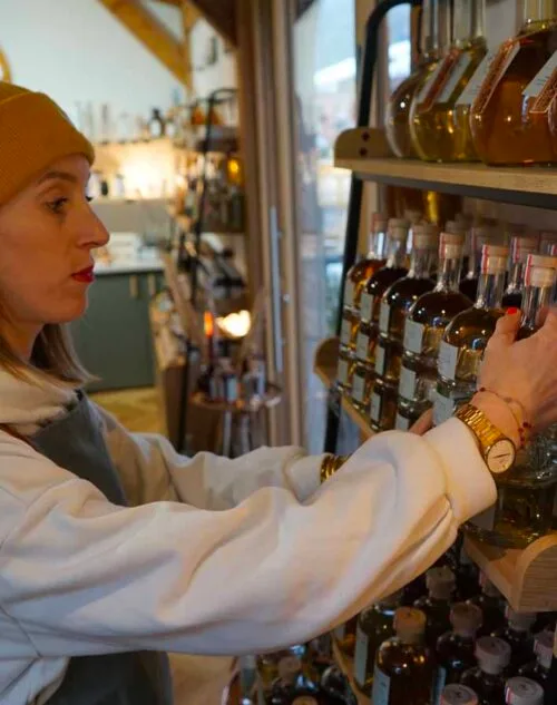 Photo de Roxane Mengoli en train de poser un flacon de spiritueux sur une étagère dans la distillerie Maison M.